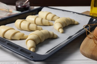 Photo of Raw croissants on white wooden table, closeup