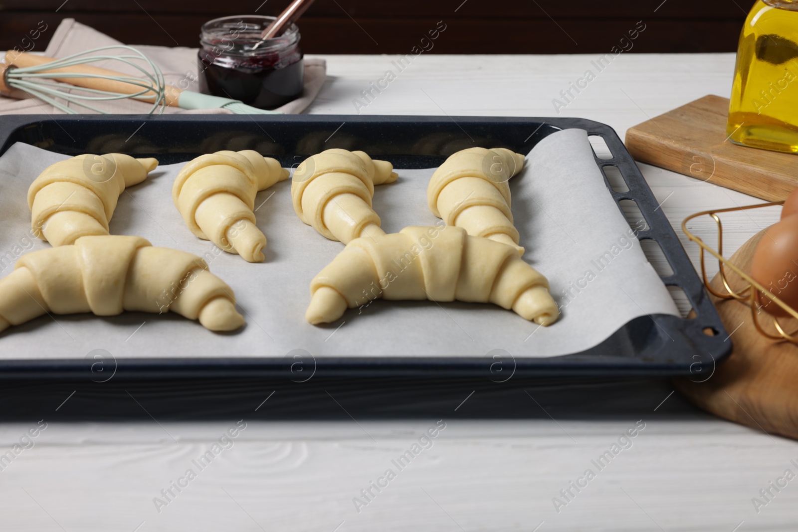 Photo of Raw croissants on white wooden table, closeup