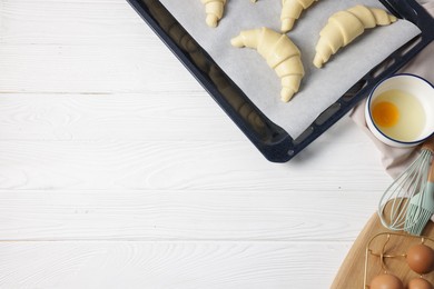 Raw croissants and eggs on white wooden table, flat lay. Space for text