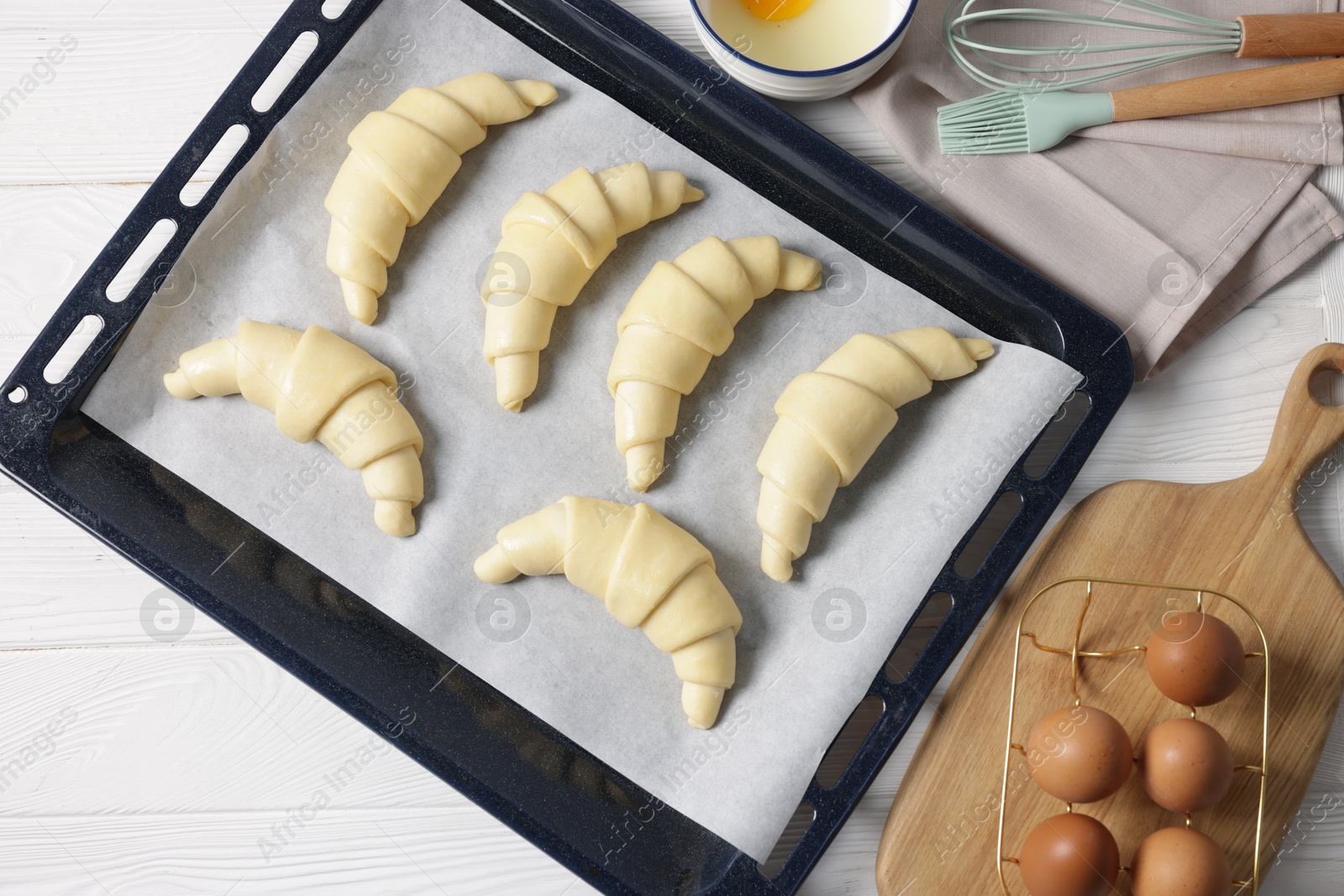 Photo of Raw croissants and eggs on white wooden table, flat lay