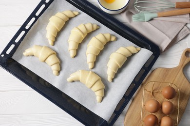 Raw croissants and eggs on white wooden table, flat lay