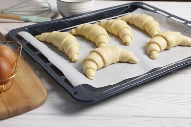 Photo of Raw croissants and eggs on white wooden table, closeup