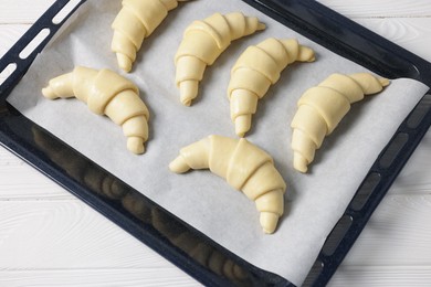 Raw croissants on white wooden table, top view