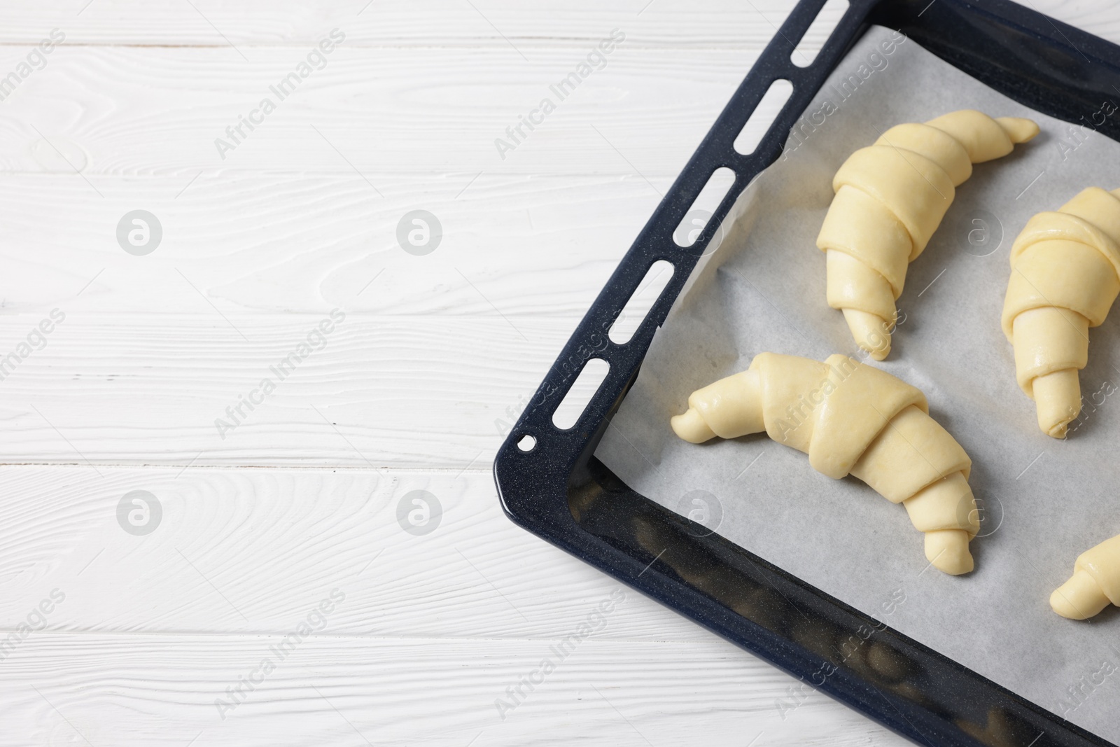 Photo of Raw croissants on white wooden table, top view. Space for text