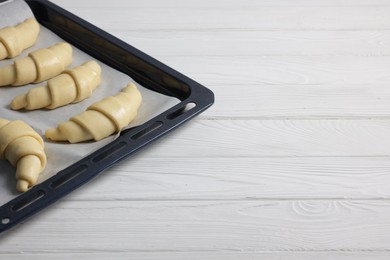 Photo of Raw croissants on white wooden table, closeup. Space for text