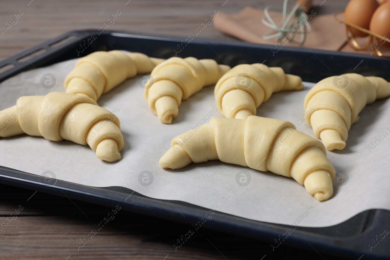 Photo of Fresh raw croissants on wooden table, closeup