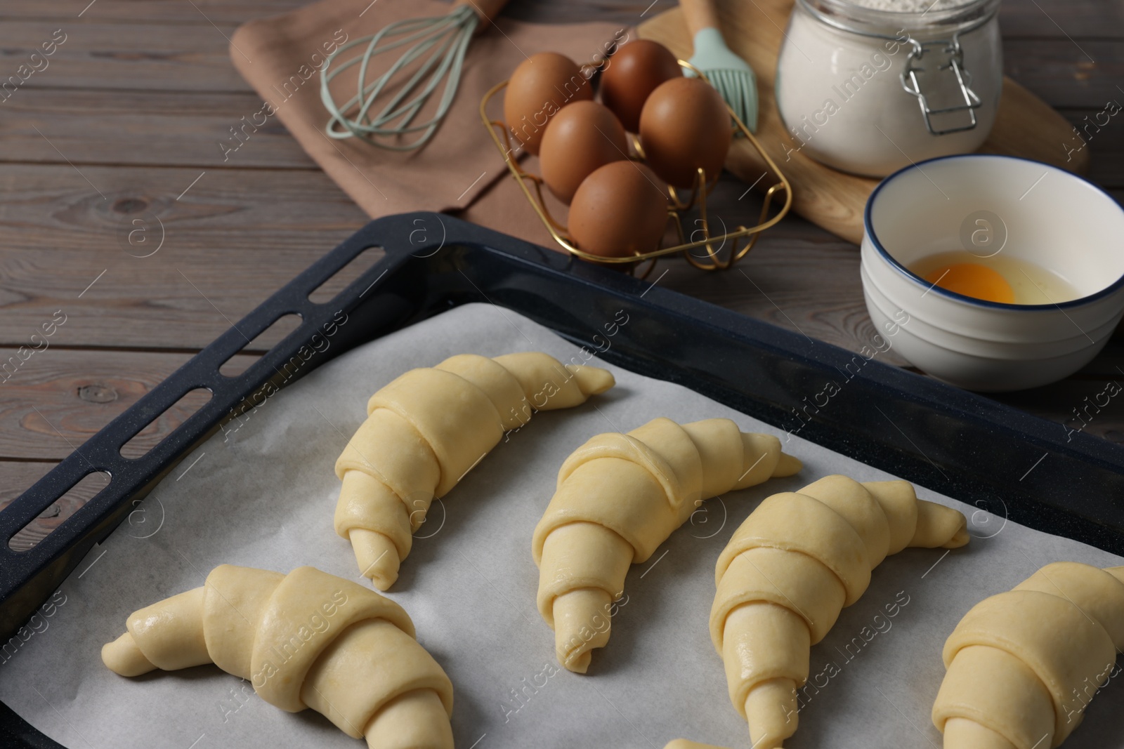 Photo of Raw croissants and ingredients on wooden table, closeup