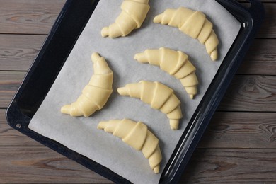 Raw croissants on wooden table, top view