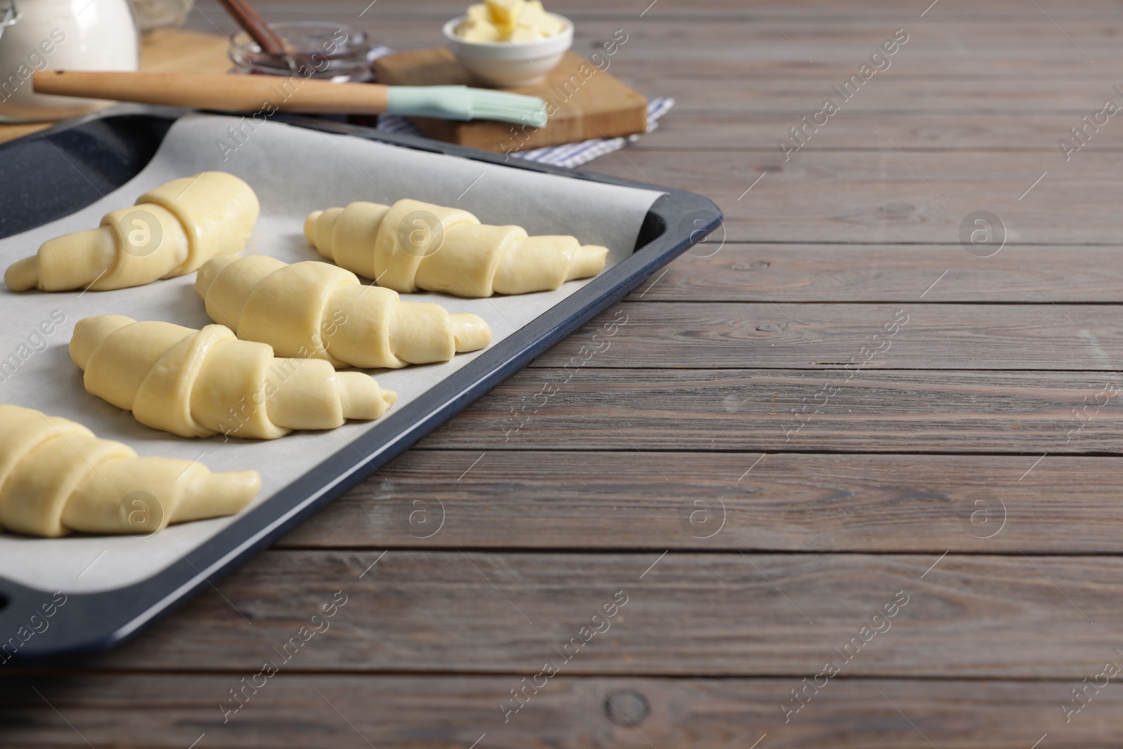 Photo of Raw croissants on wooden table, closeup. Space for text