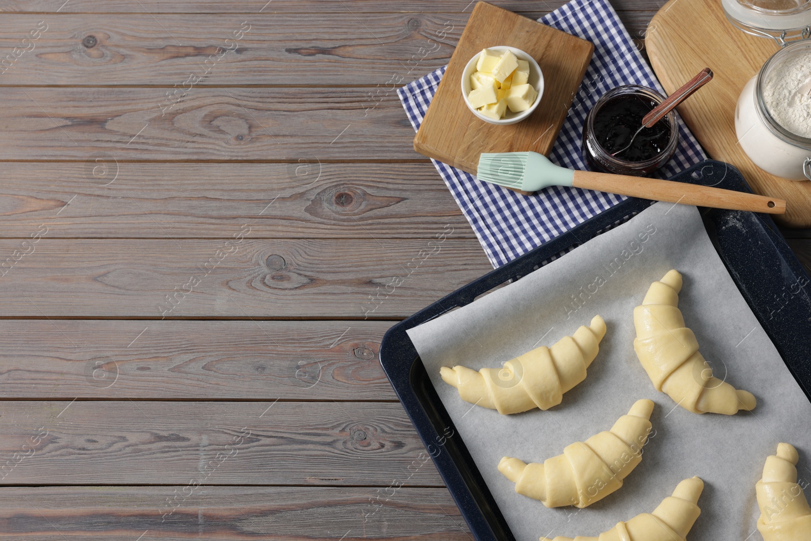 Photo of Raw croissants, ingredients and kitchenware on wooden table, flat lay. Space for text