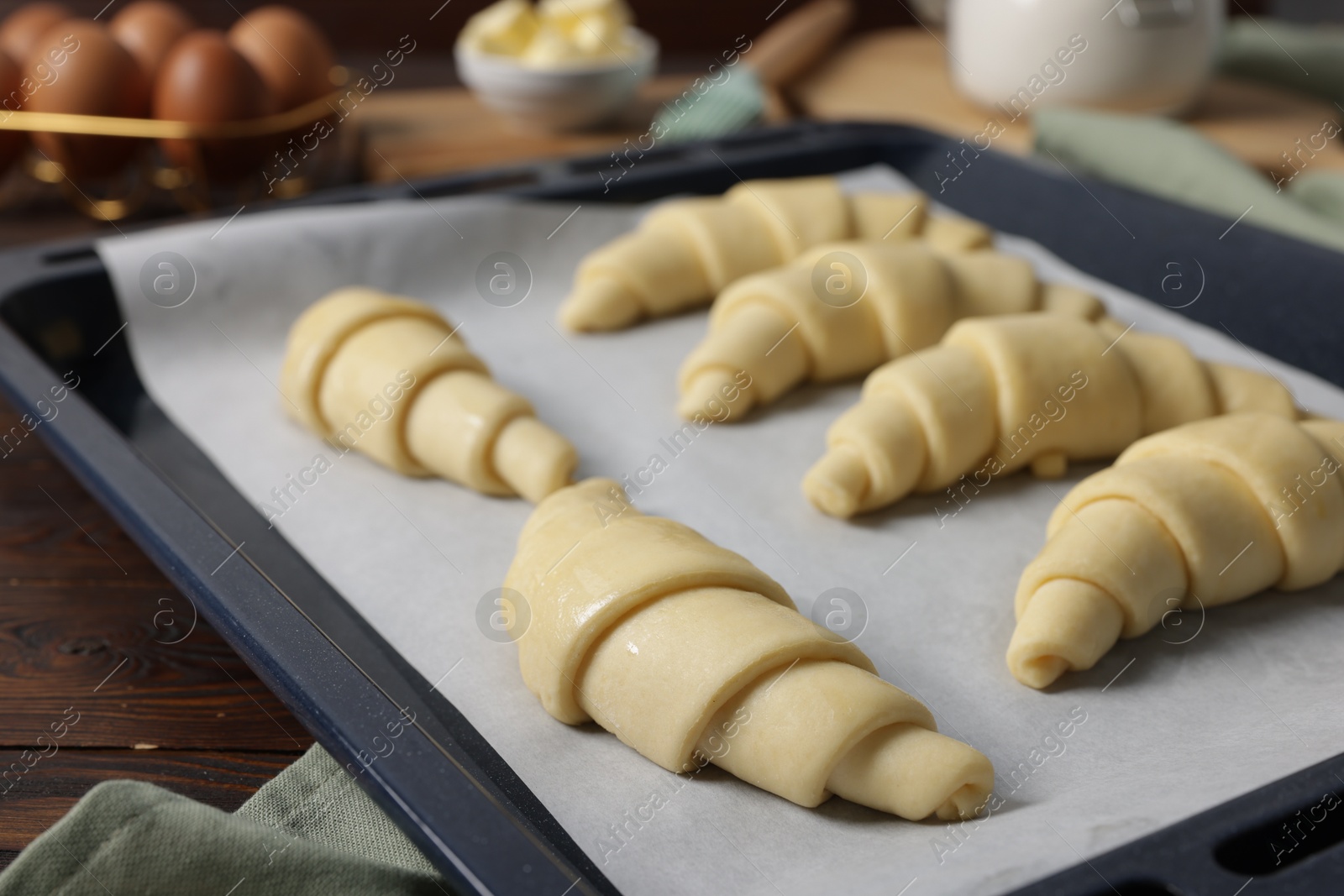 Photo of Fresh raw croissants on wooden table, closeup