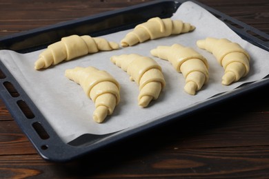 Fresh raw croissants on wooden table, closeup