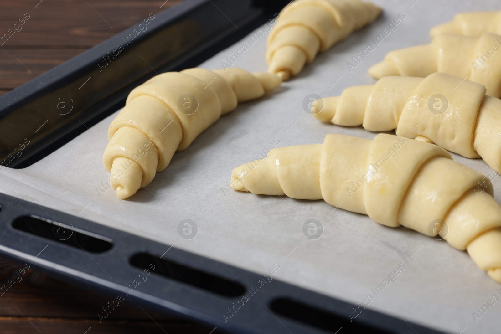 Photo of Fresh raw croissants on wooden table, closeup