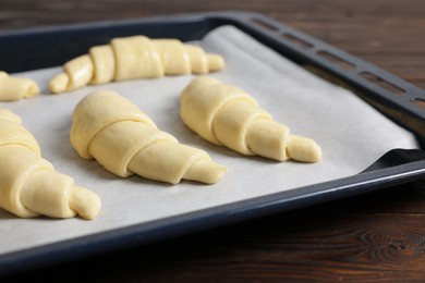 Photo of Fresh raw croissants on wooden table, closeup