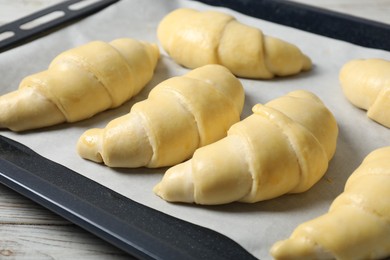 Raw croissants on wooden table, closeup view