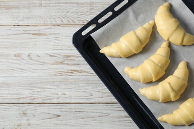 Photo of Raw croissants on wooden table, top view. Space for text