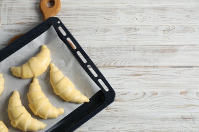 Photo of Raw croissants on wooden table, top view. Space for text