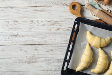 Photo of Raw croissants and kitchenware on wooden table, flat lay. Space for text