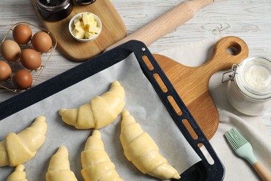 Photo of Raw croissants, ingredients and kitchenware on wooden table, flat lay