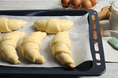 Raw croissants and eggs on wooden table, closeup