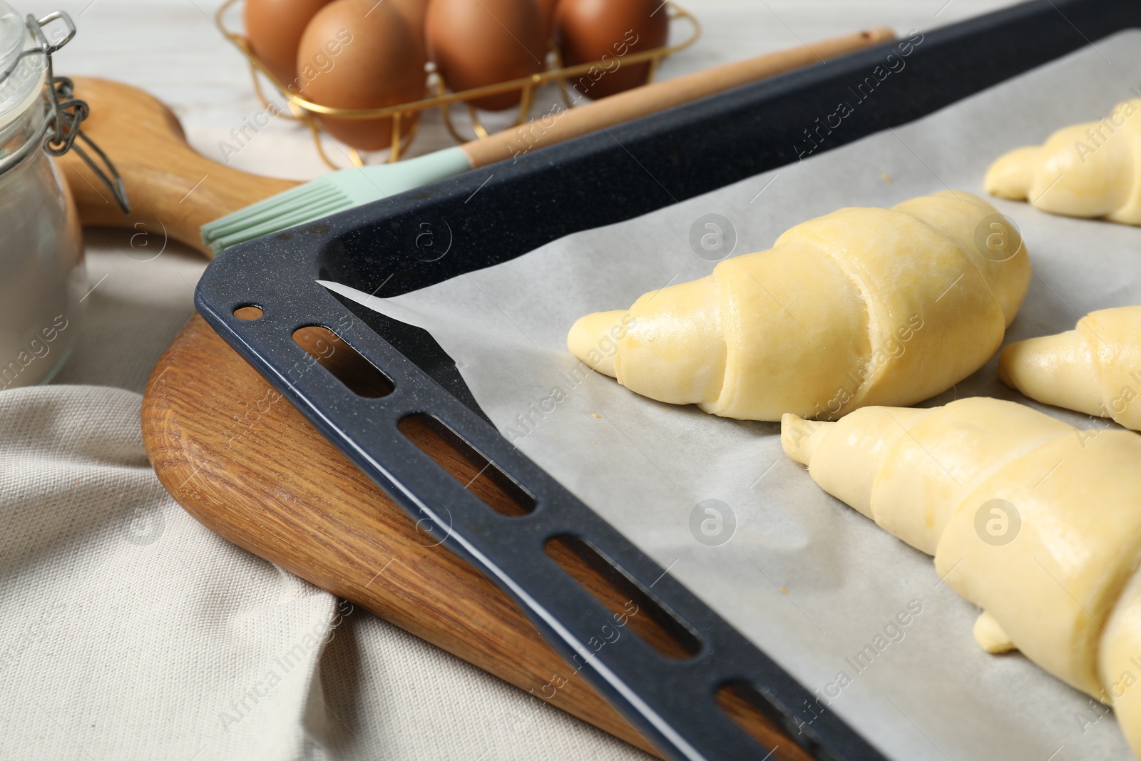 Photo of Raw croissants and eggs on wooden table, closeup