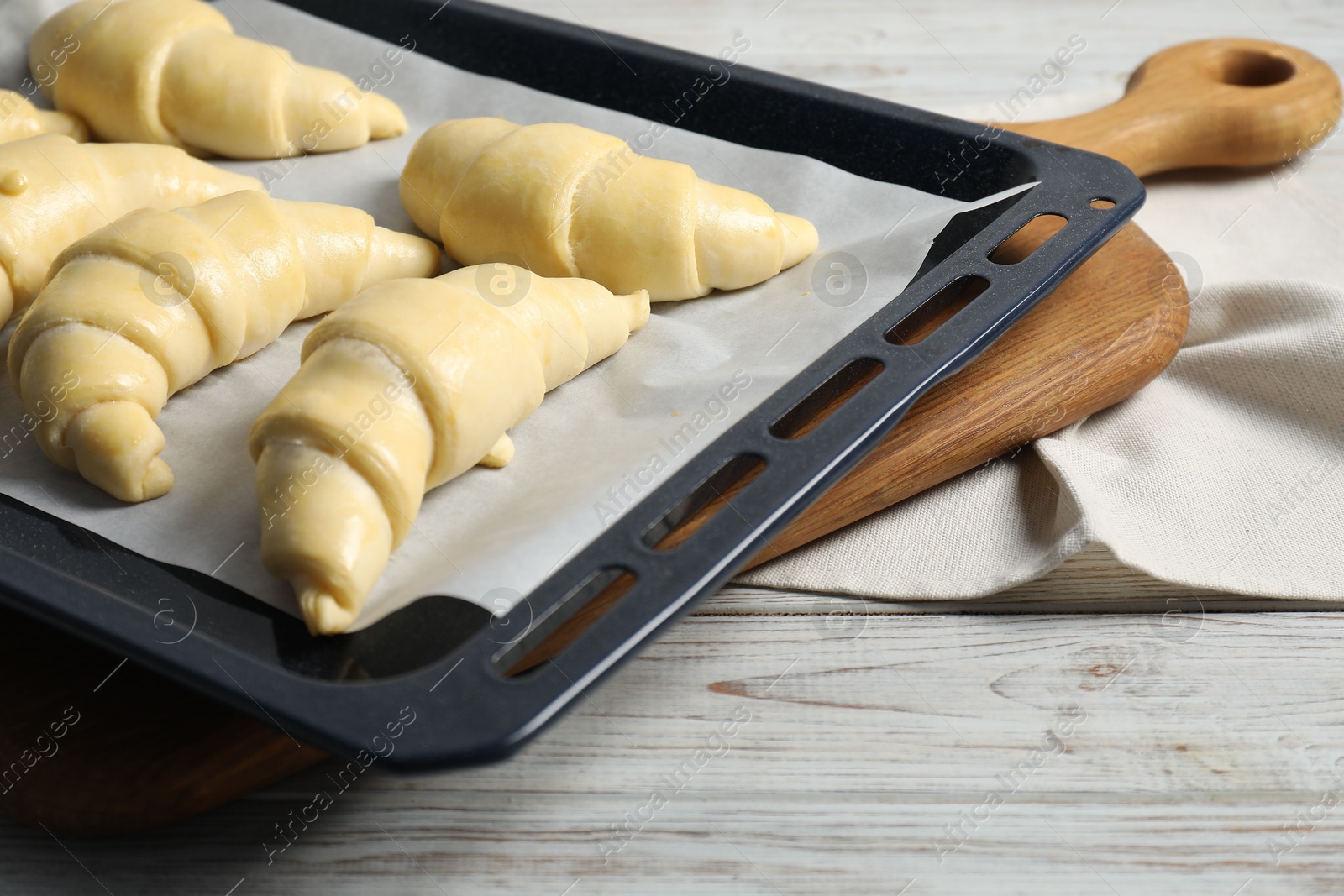 Photo of Raw croissants on wooden table, closeup view