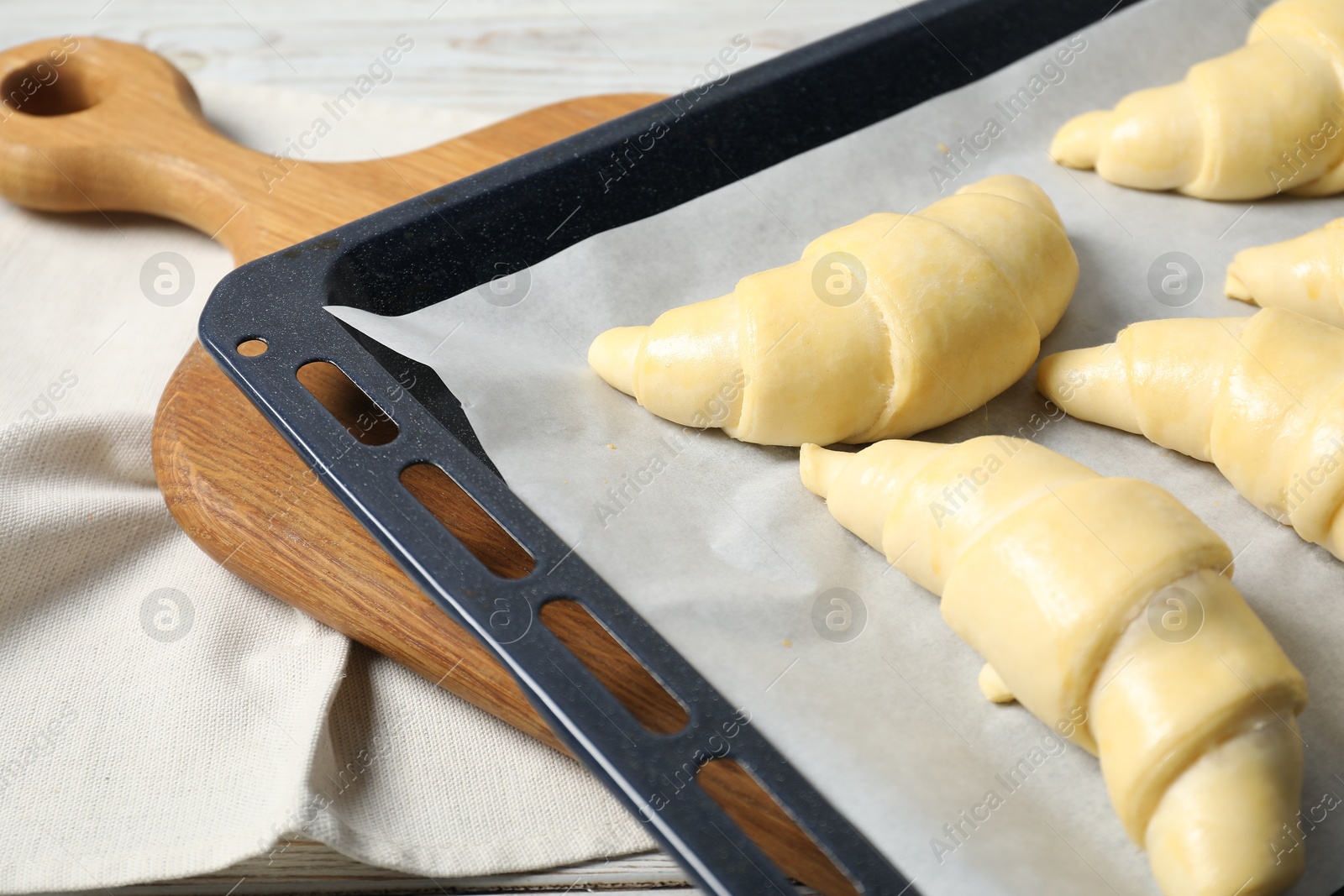 Photo of Fresh raw croissants on wooden table, closeup