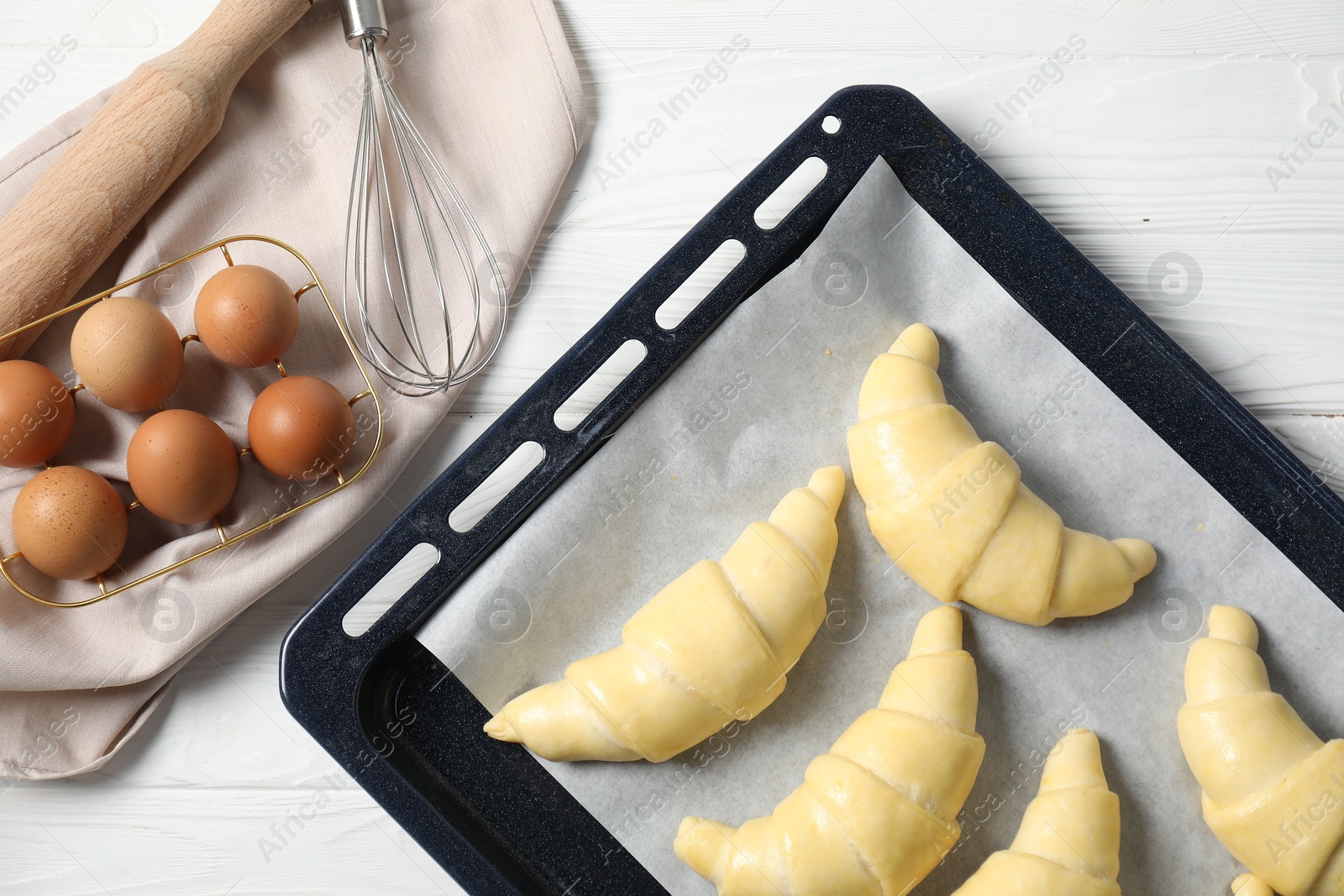 Photo of Raw croissants and eggs on white wooden table, flat lay