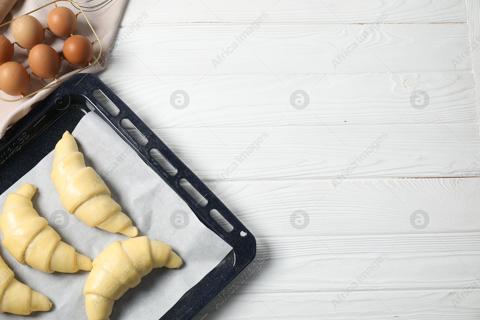 Photo of Raw croissants and eggs on white wooden table, flat lay. Space for text