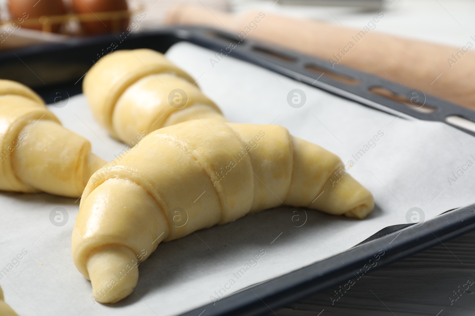 Photo of Fresh raw croissants on wooden table, closeup