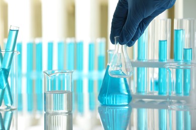 Photo of Woman with laboratory glassware at table indoors, closeup