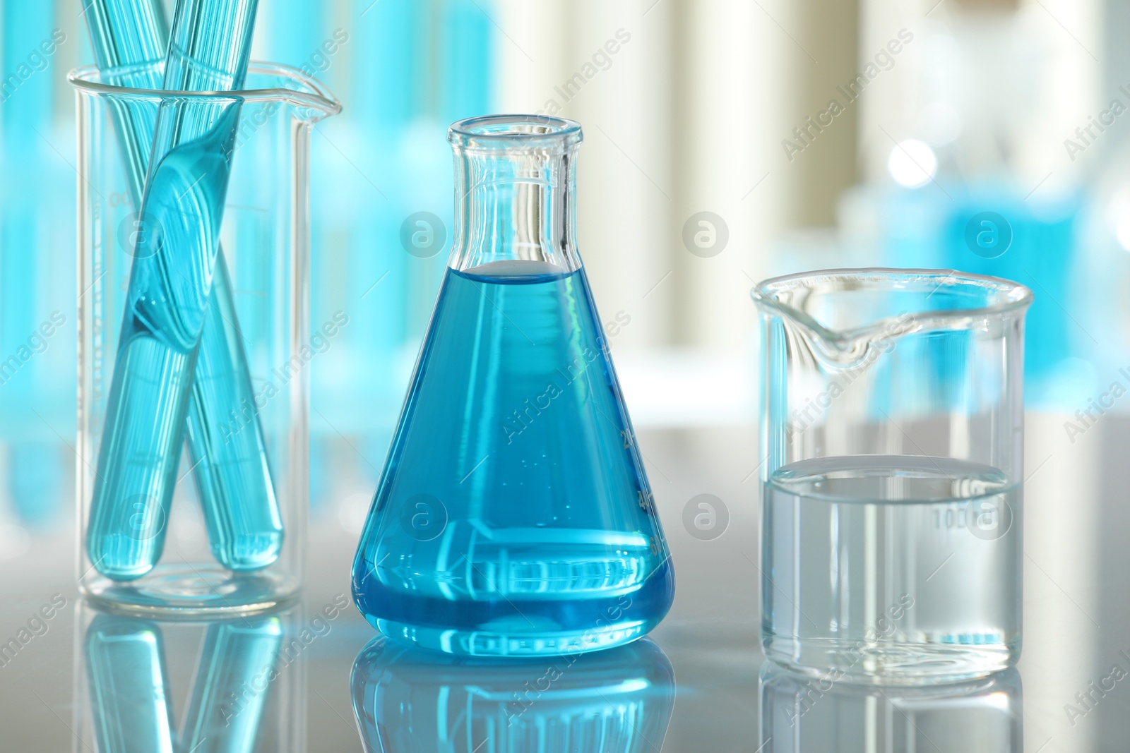 Photo of Laboratory glassware with liquid on mirror surface indoors, closeup