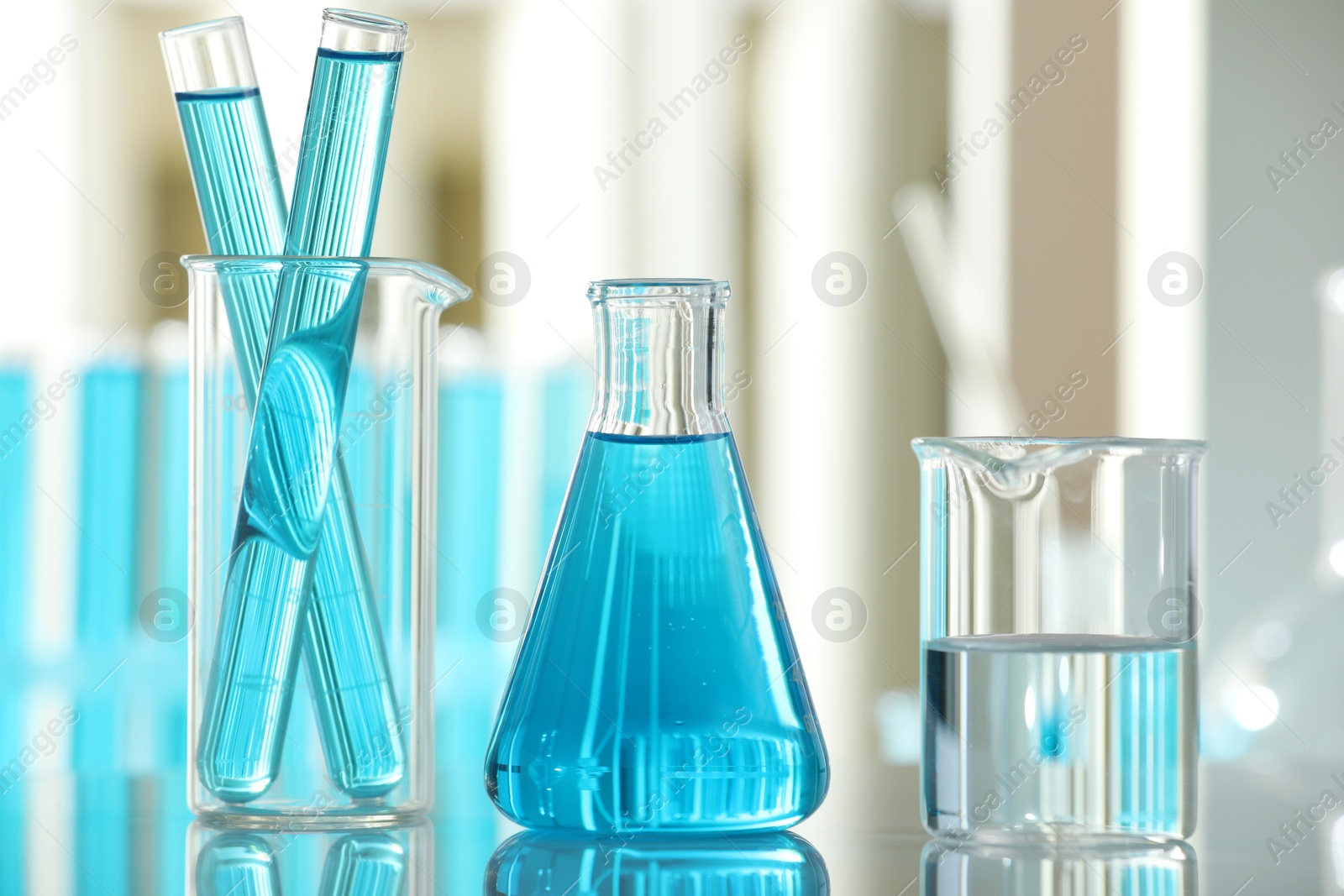 Photo of Laboratory glassware with liquid on mirror surface indoors, closeup