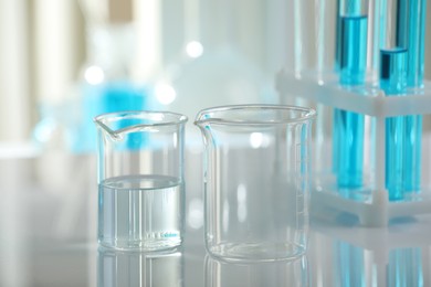 Photo of Laboratory glassware with liquid on mirror surface indoors, closeup