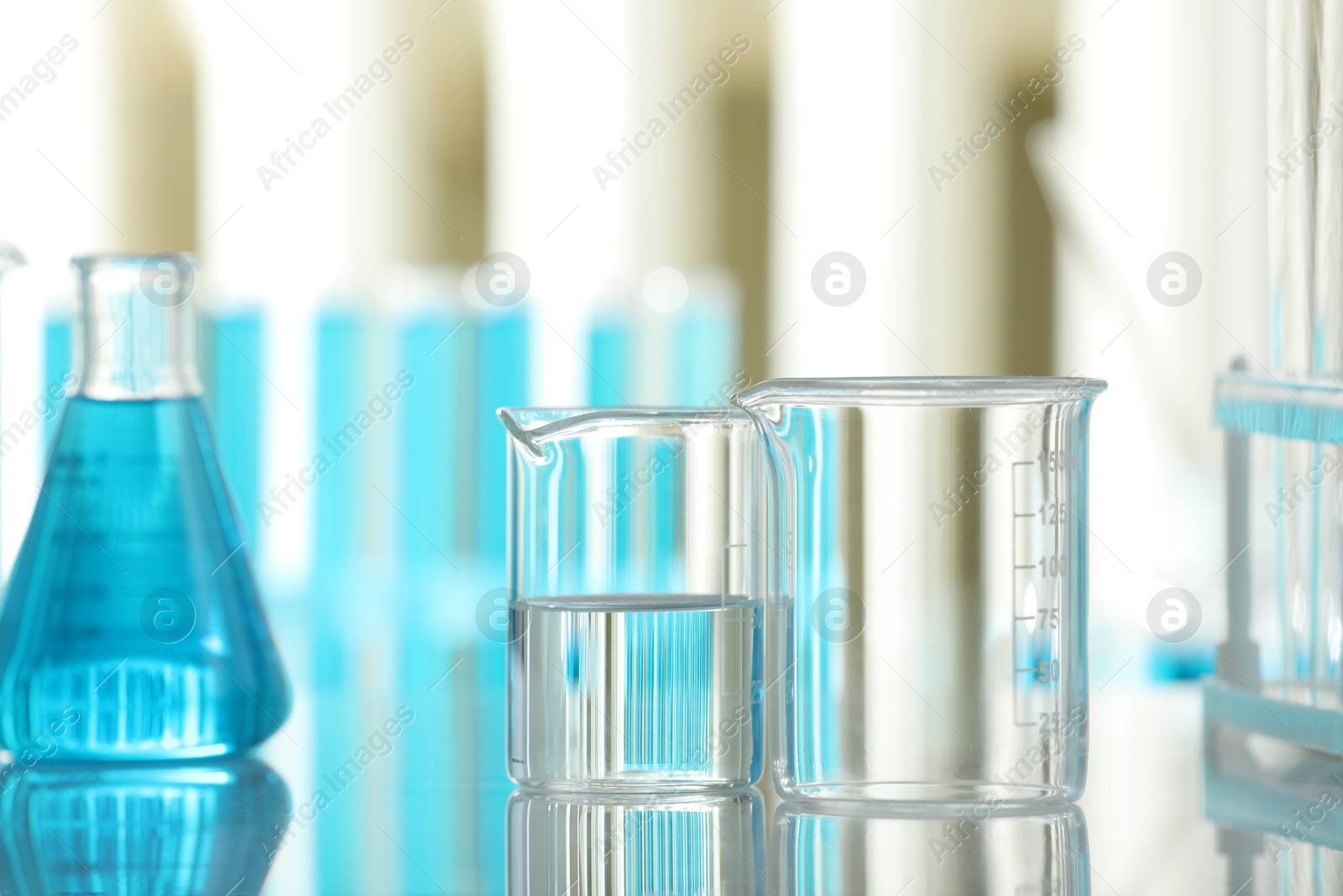 Photo of Laboratory glassware with liquid on mirror surface indoors