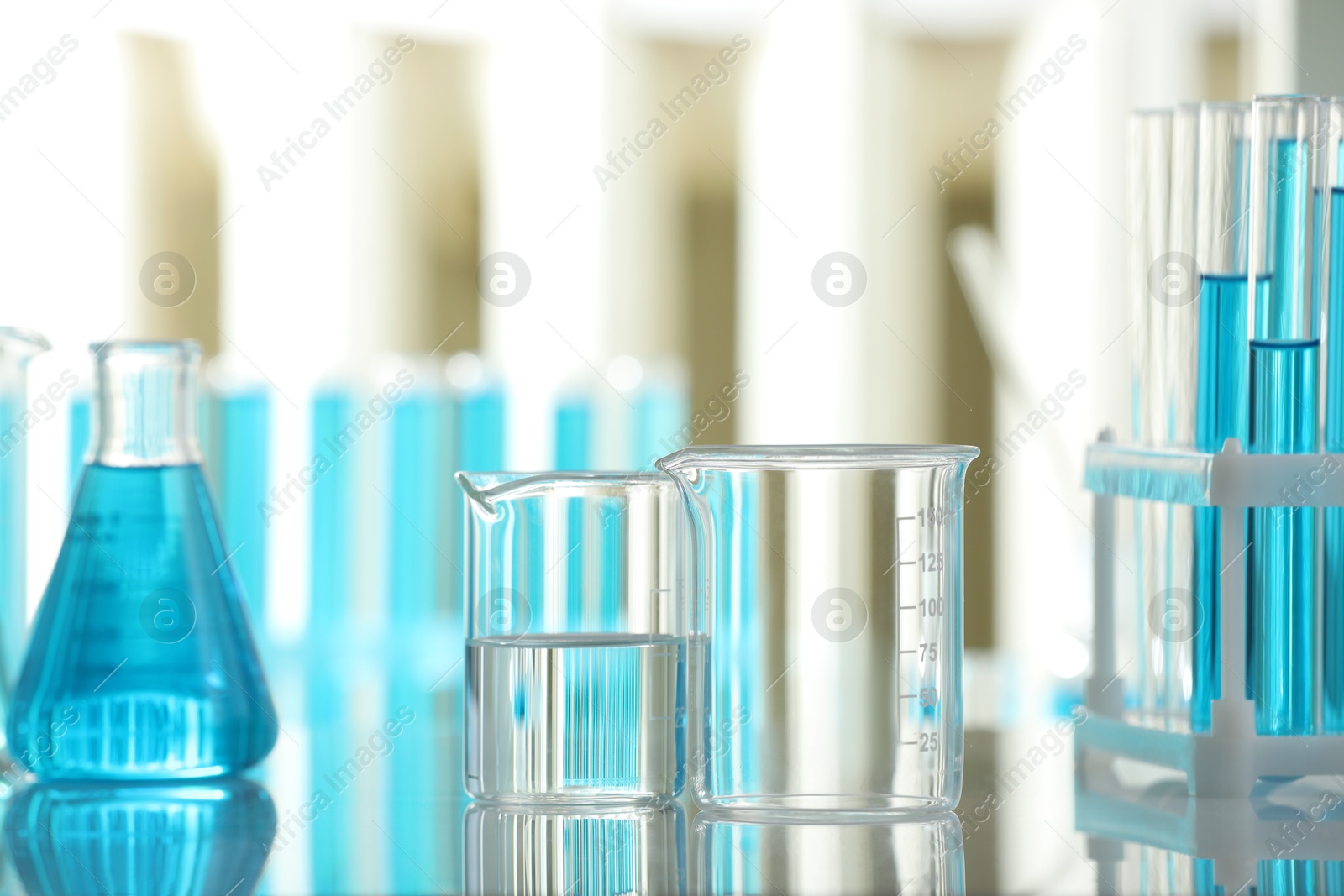 Photo of Laboratory glassware with liquid on mirror surface indoors