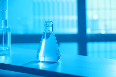 Photo of Conical flask with blue liquid on table indoors, color toned effect. Space for text