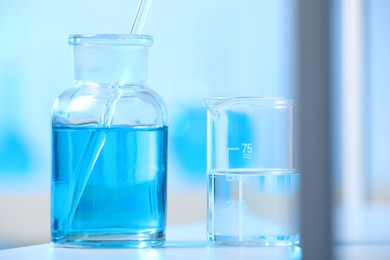 Photo of Laboratory glassware with liquid on shelf indoors, closeup