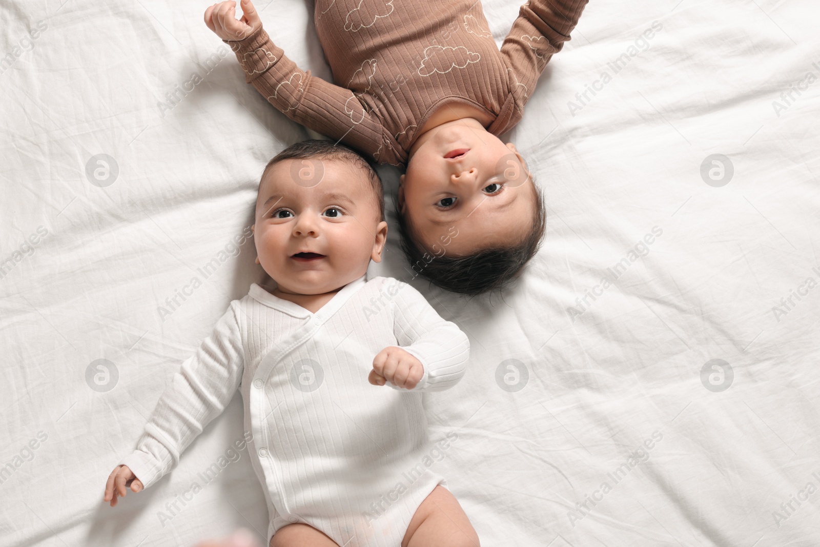 Photo of Cute twin babies resting on bed indoors, top view