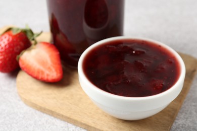 Photo of Delicious strawberry sauce and fresh berries on light table, closeup