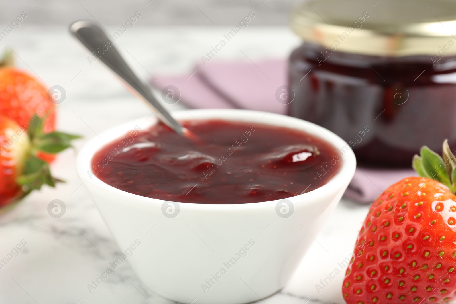 Photo of Delicious strawberry sauce and fresh berries on white marble table, closeup