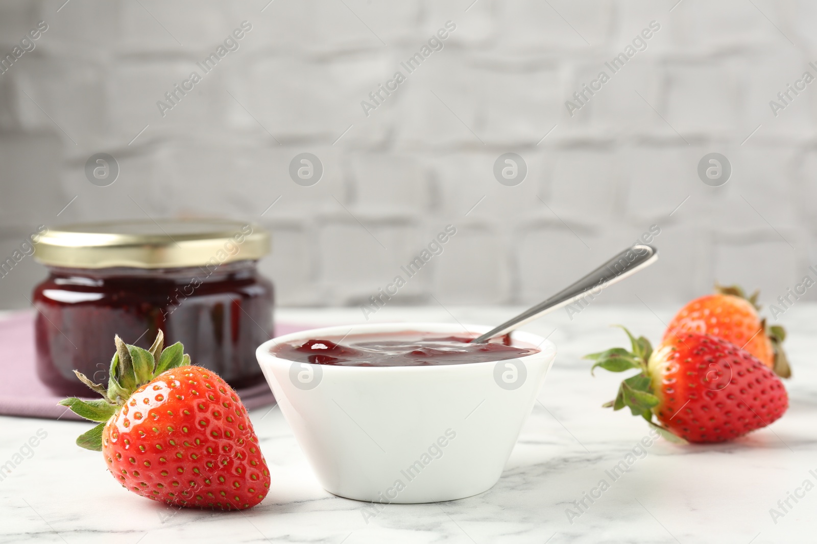 Photo of Delicious strawberry sauce and fresh berries on white marble table. Space for text