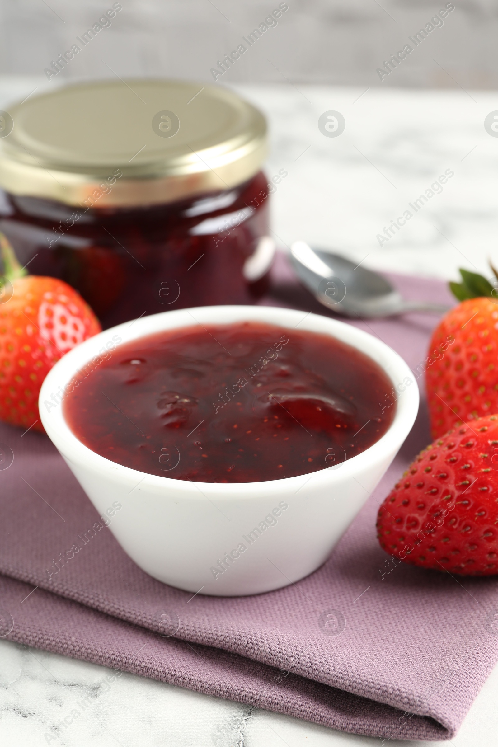 Photo of Delicious strawberry sauce and fresh berries on white marble table, closeup