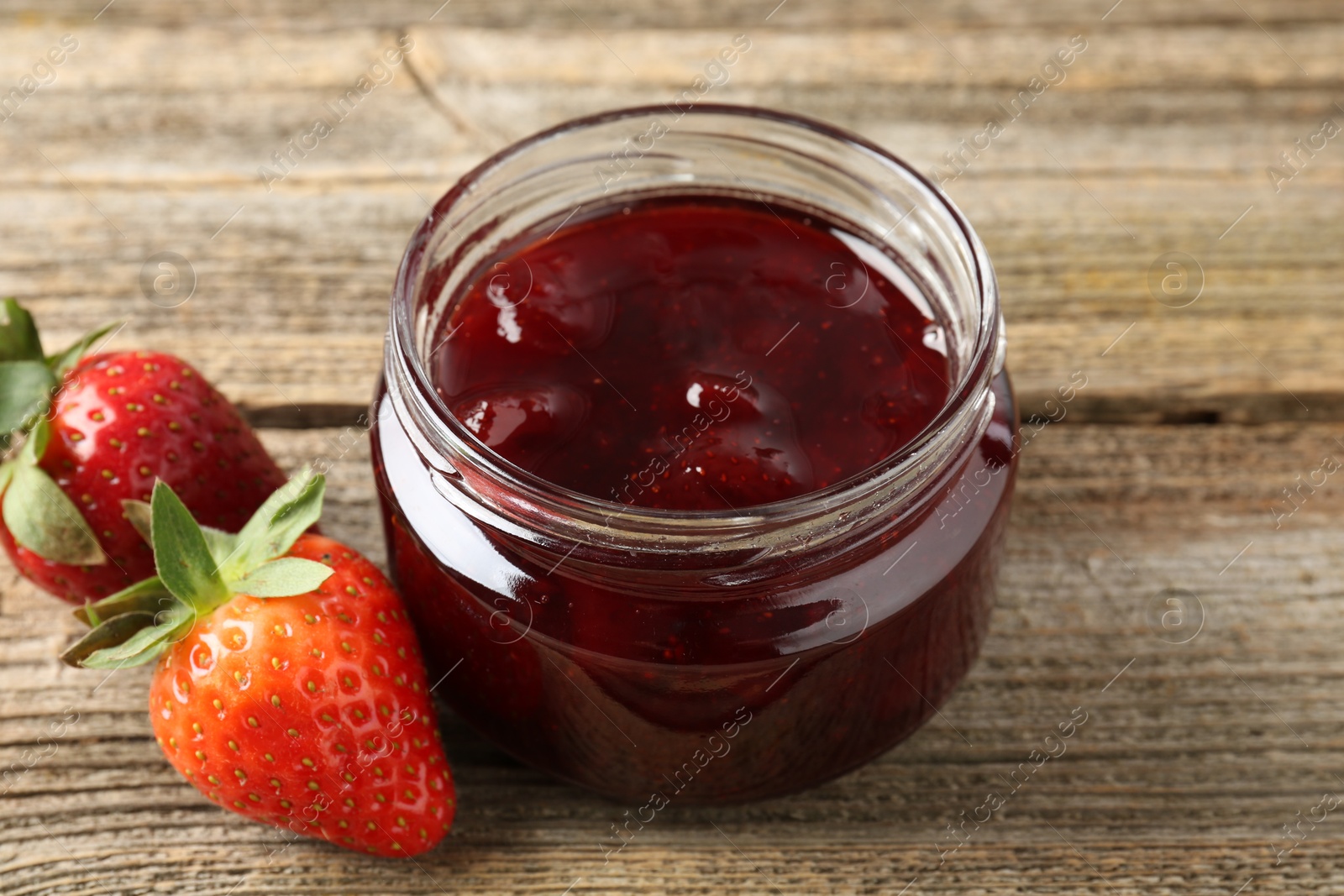 Photo of Delicious strawberry sauce and fresh berries on wooden table, closeup