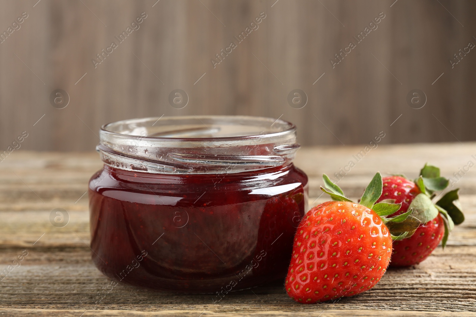 Photo of Delicious strawberry sauce and fresh berries on wooden table, closeup