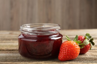 Photo of Delicious strawberry sauce and fresh berries on wooden table, closeup