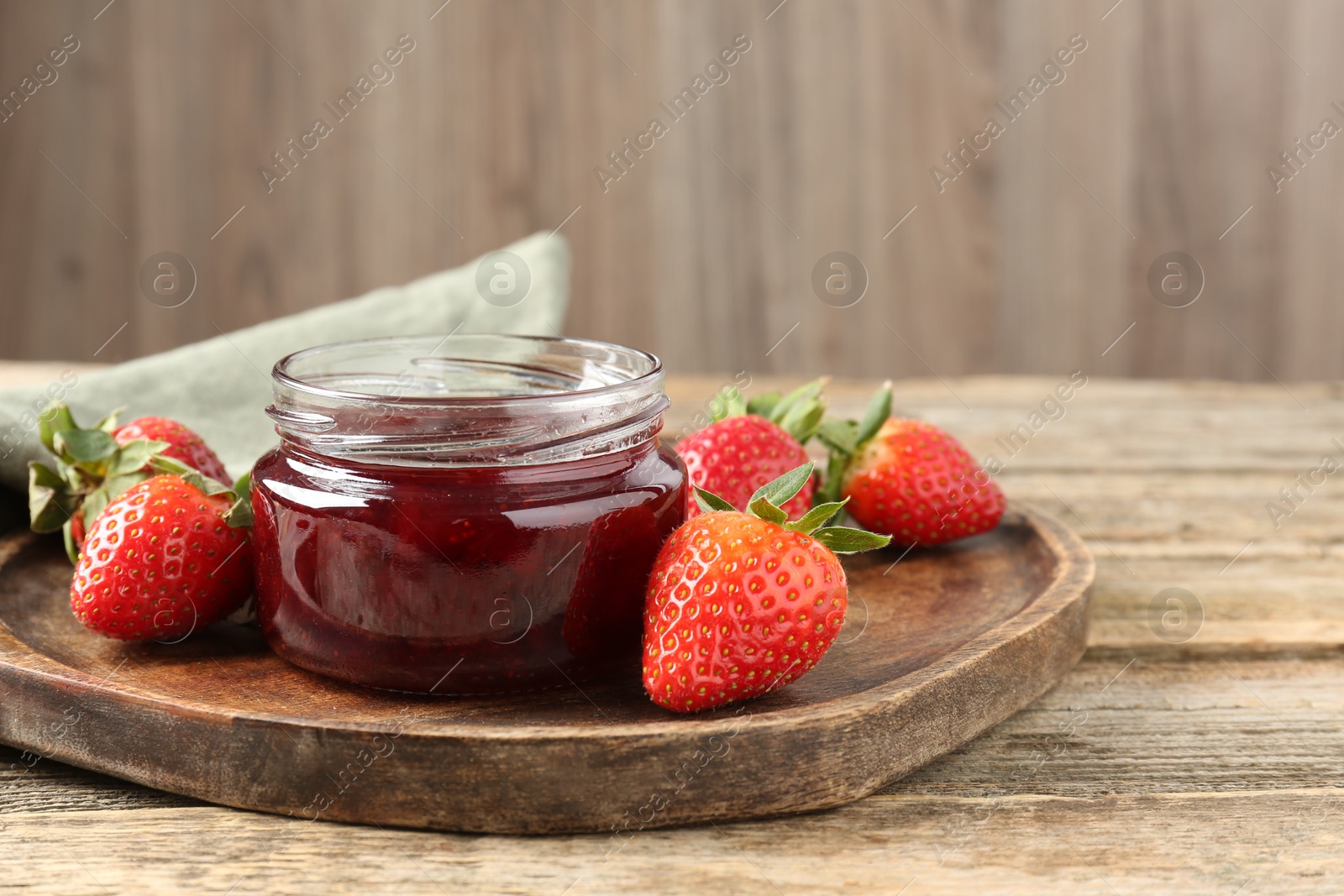 Photo of Delicious strawberry sauce and fresh berries on wooden table, closeup. Space for text