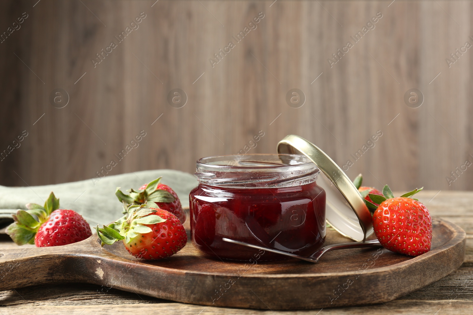 Photo of Delicious strawberry sauce and fresh berries on wooden table. Space for text