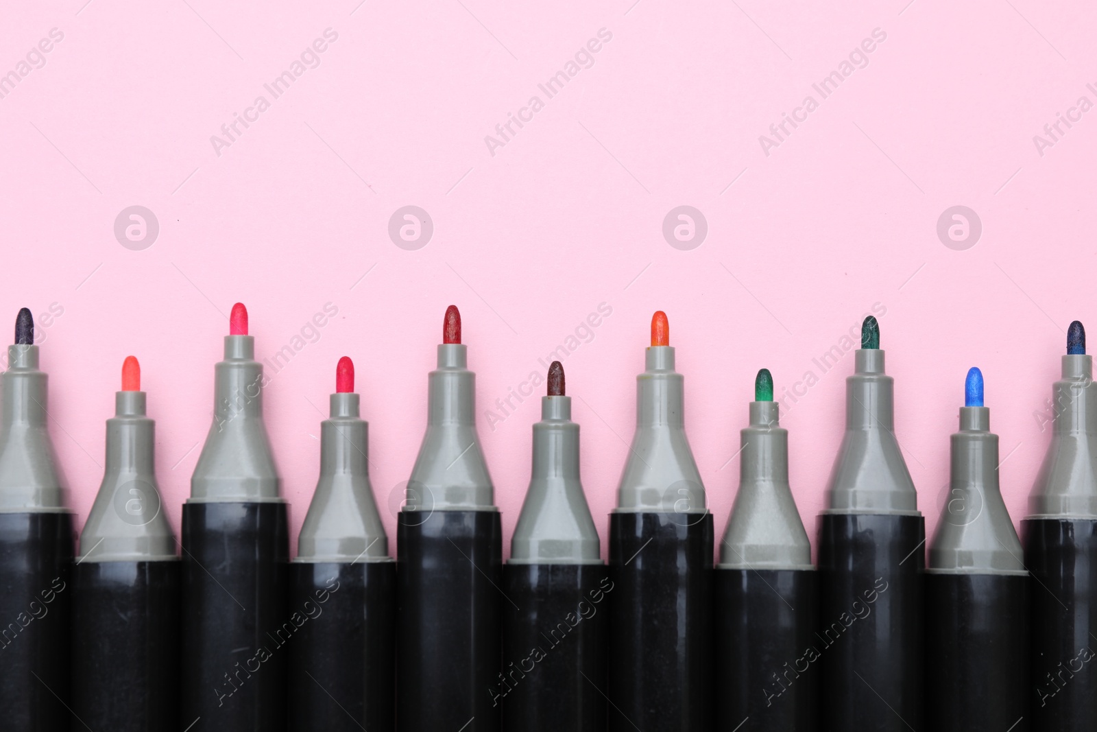 Photo of Colorful markers on light pink background, top view. Space for text