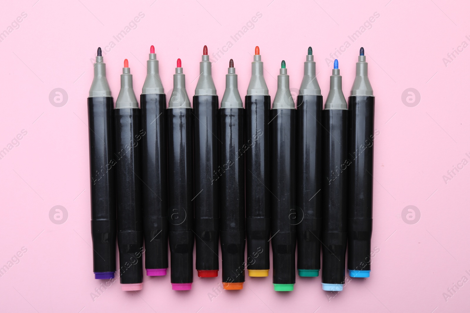 Photo of Colorful double sided markers on light pink background, top view